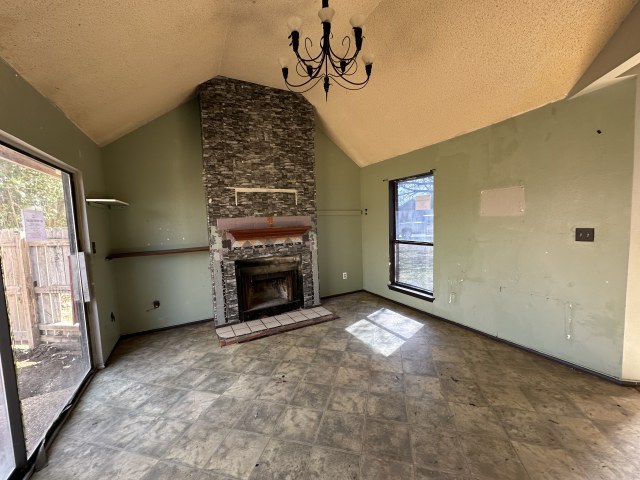 548 Spring River Drive Martindale, TX 78655 - Photo 8 of 17 Unfurnished living room with a high textured ceiling, a stone fireplace, and hanging lights