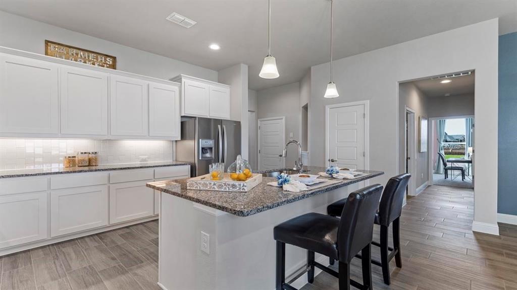11205 Treehouse Trail Justin, TX 76247 - Photo 5 of 39 a kitchen with kitchen island granite countertop a sink and white cabinets