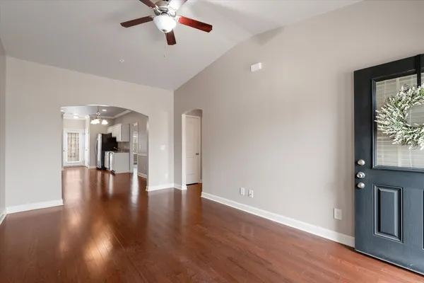 a view of an empty room with wooden floor and a window