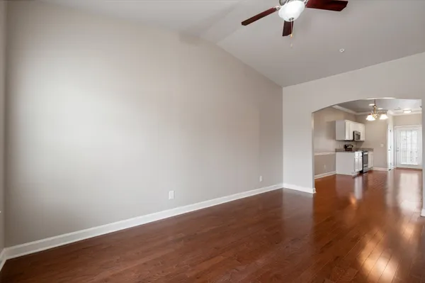 a view of a hallway with wooden floor and a kitchen