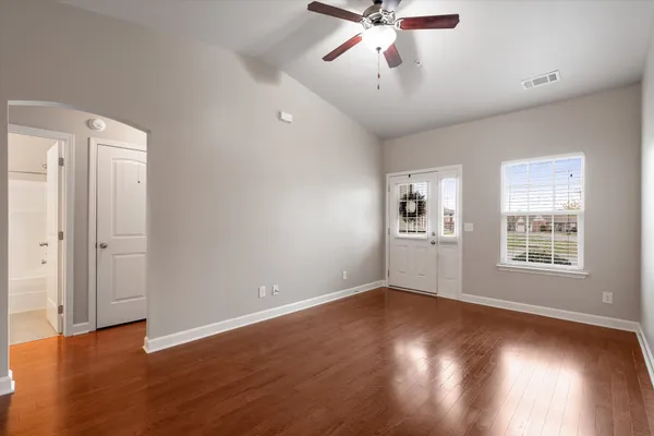 a view of a room with wooden floor and a ceiling fan