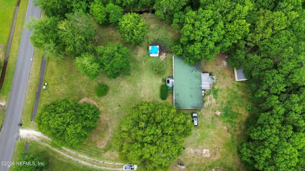 an aerial view of residential house with outdoor space and trees all around