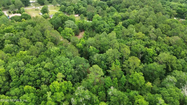 an aerial view of residential house with outdoor space and trees all around