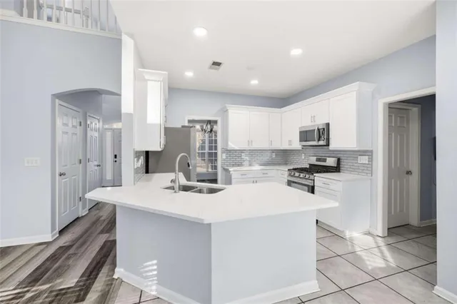 a kitchen with stainless steel appliances kitchen island granite countertop a sink a stove a refrigerator cabinets and chairs