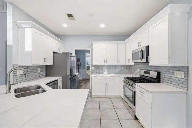 a kitchen with a sink a stove a refrigerator and white cabinets