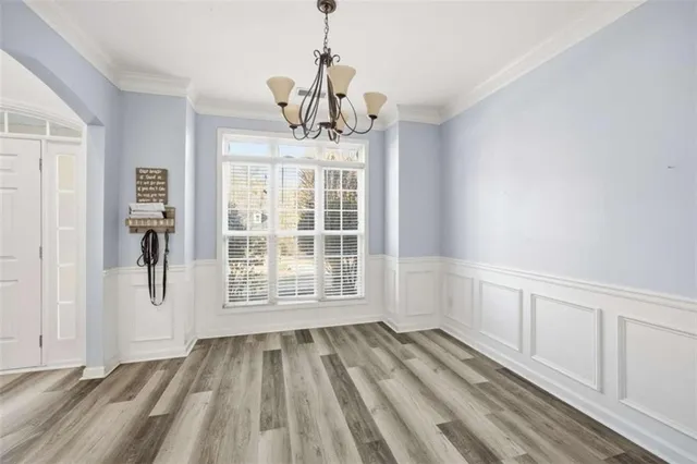 a view of an empty room with wooden floor and windows