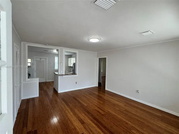 an empty room with wooden floor and mirror