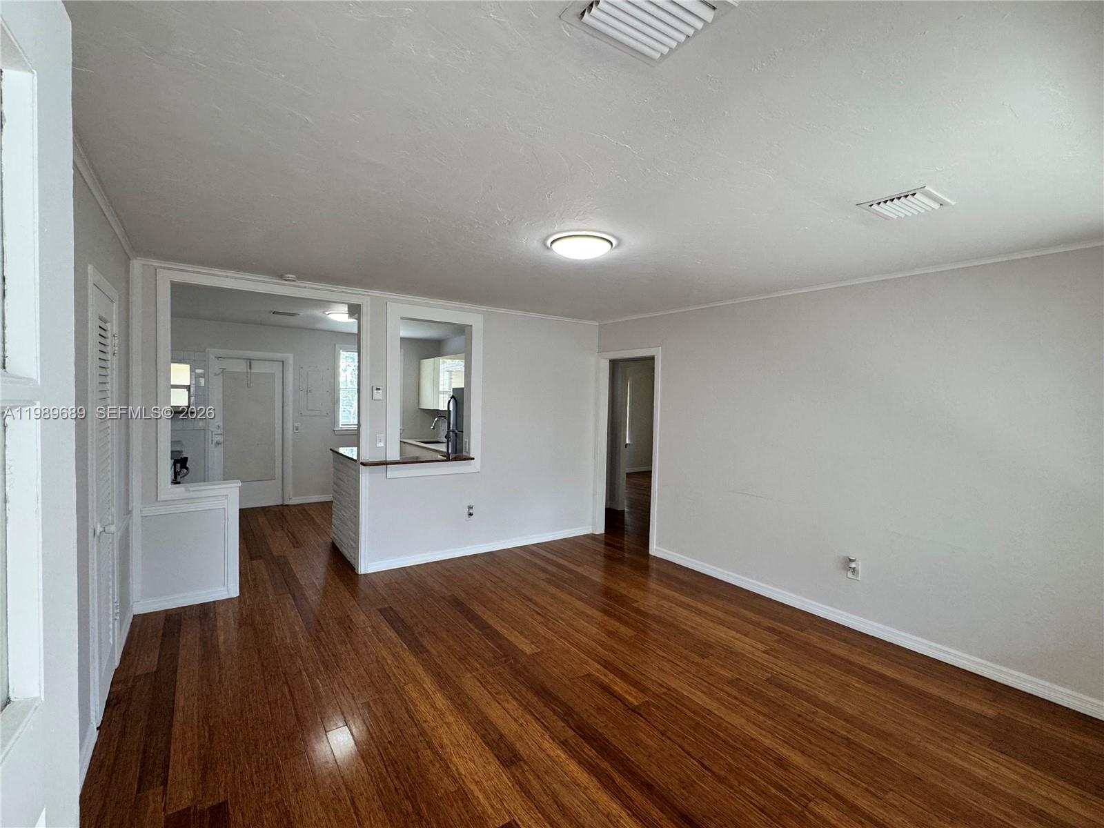 1441 Northeast 134th Road, Unit 2 North Miami, FL 33161 - Photo 1 of 16 an empty room with wooden floor and mirror
