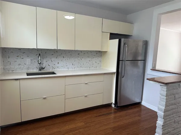 a kitchen with a sink a refrigerator and cabinets