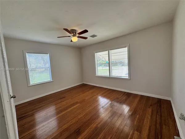 a view of an empty room with a window and wooden floor