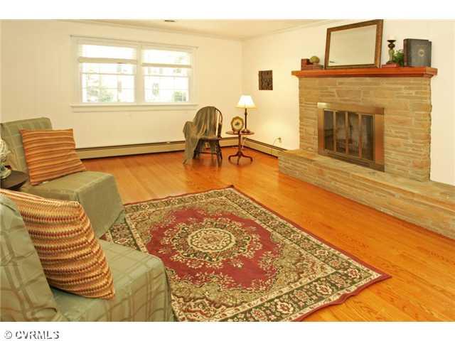 5116 Sylvan Road Richmond, VA 23225 - Photo 6 of 12 Den/Family/Great Room - FAMILY ROOM located to the left of the entryway and with access to the kitchen, features crown molding, classic paneled walls, a stacked-stone woodburning fireplace with an extended hearth bench, and hardwood floors.