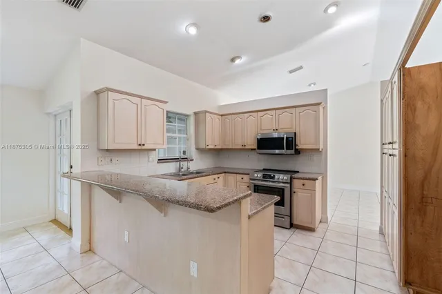 a kitchen with stainless steel appliances granite countertop a stove top oven a sink and a granite counter top