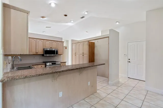 a view of a kitchen with stainless steel appliances granite countertop a refrigerator and a sink