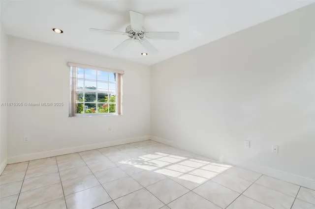an empty room with windows and chandelier fan