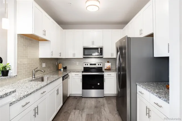 a kitchen with granite countertop a refrigerator stove and sink