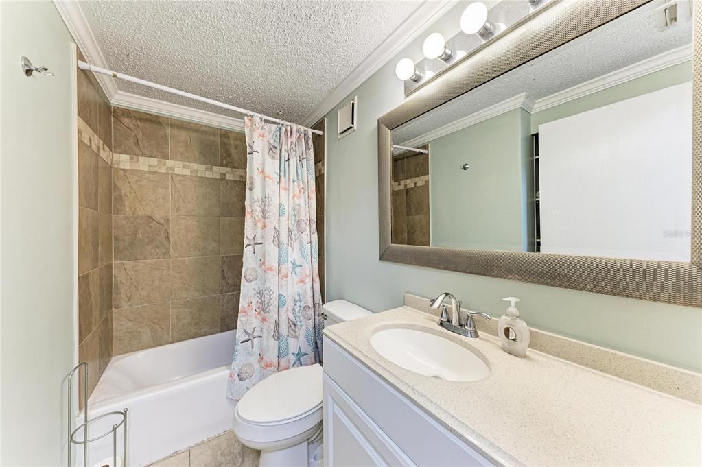 1581 Royal Road Venice, FL 34293 - Photo 32 of 41 a bathroom with a granite countertop sink a toilet a mirror a bathtub and shower