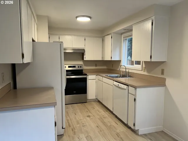 a kitchen with granite countertop a refrigerator stove and sink