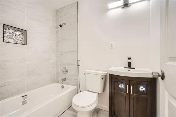 a bathroom with a granite countertop sink a toilet and shower