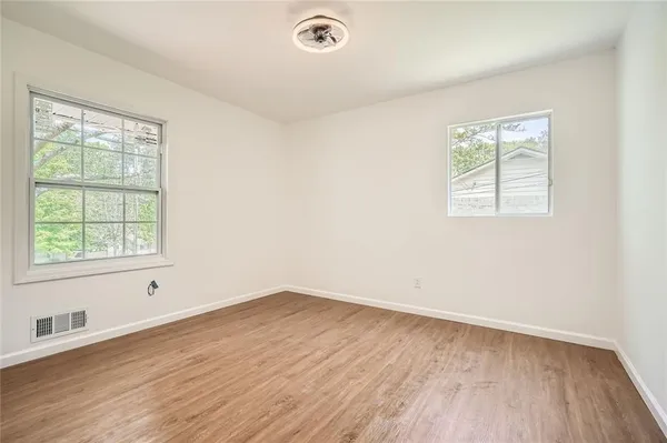an empty room with wooden floor and windows