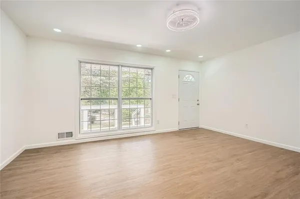 an empty room with wooden floor and windows