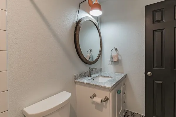 a bathroom with a granite countertop toilet a sink and a mirror