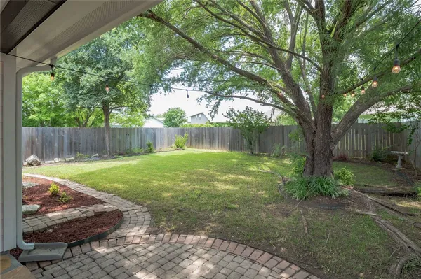 a view of a backyard with large trees and wooden fence