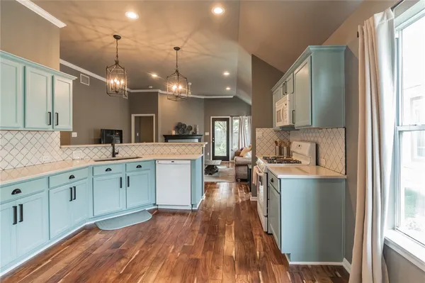 a kitchen with stainless steel appliances granite countertop a sink dishwasher a stove and white countertops with wooden floor