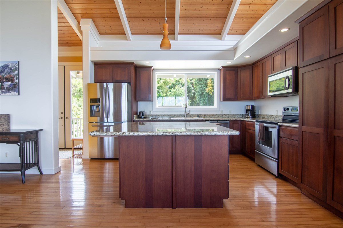 82-1135 Kinue Road Captain Cook, HI 96704 - Photo 5 of 30 a kitchen with stainless steel appliances granite countertop wooden floors a stove and a refrigerator