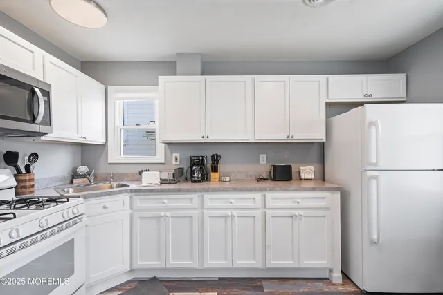a kitchen with white cabinets and white appliances