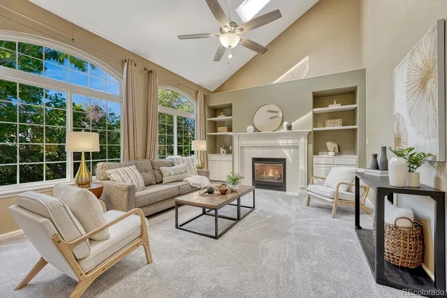 a living room with furniture a fireplace and a large window with garden view