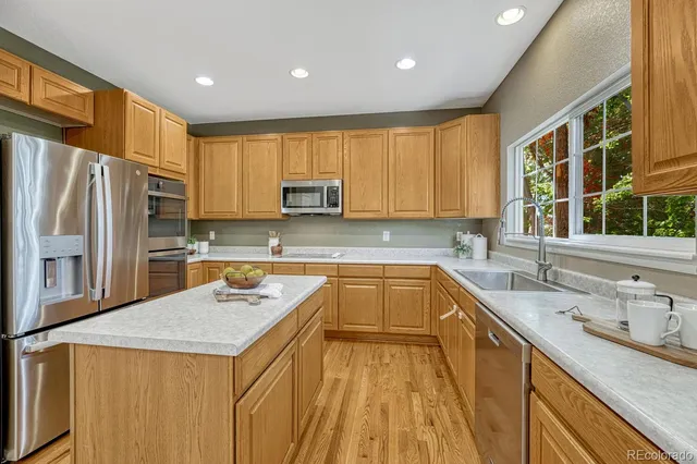 a kitchen with a sink a stove a refrigerator a center island and a window