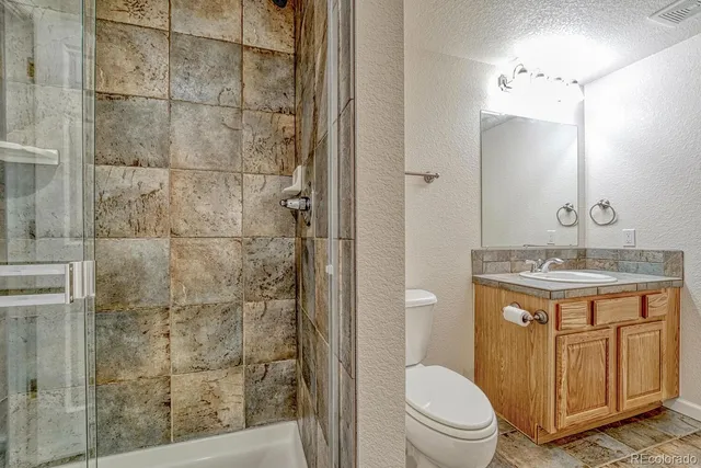 a bathroom with a granite countertop sink toilet and shower