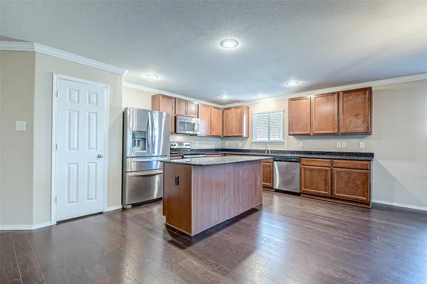 a kitchen with stainless steel appliances granite countertop a refrigerator and wooden cabinets