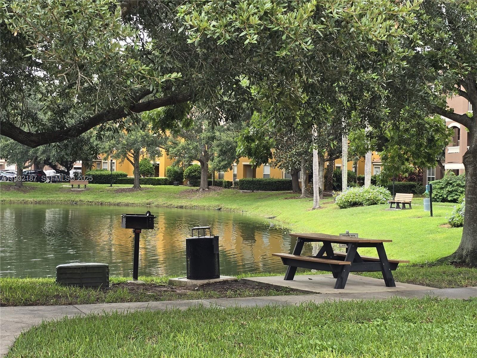 19914 Villa Creek Drive, Unit 202 Orlando, FL 32821 - Photo 14 of 19 a view of a lake with a bench and trees