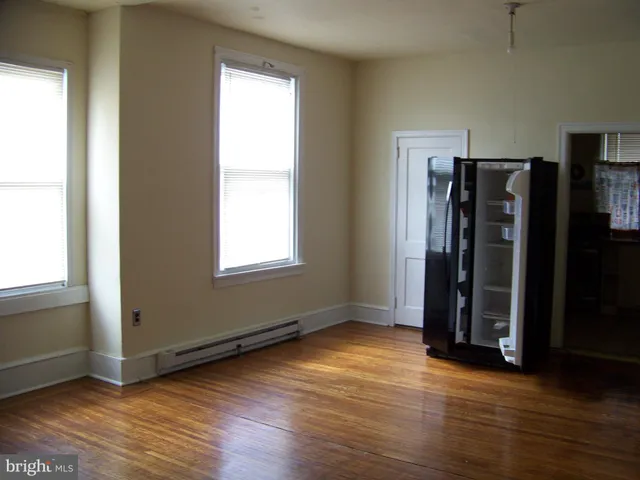 an empty room with wooden floor closet and windows