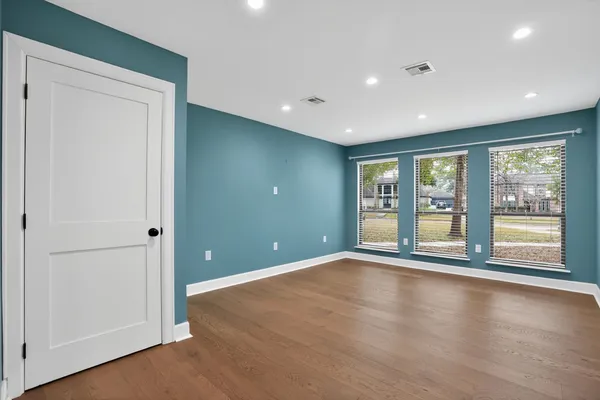 a view of an empty room with window and wooden floor