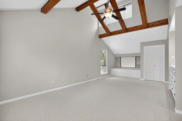 an empty room with windows and ceiling fan