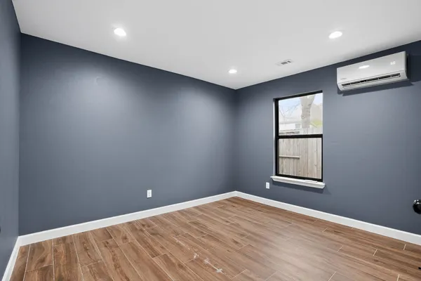 an empty room with wooden floor and windows
