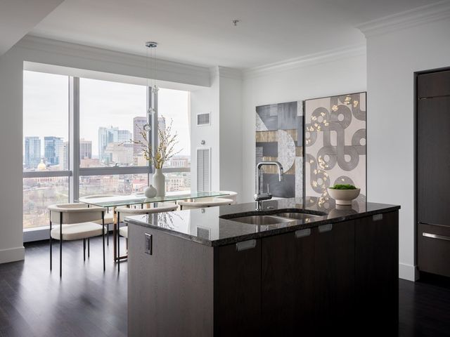 a dining hall with stainless steel appliances granite countertop a coffee table and chairs next to a large window
