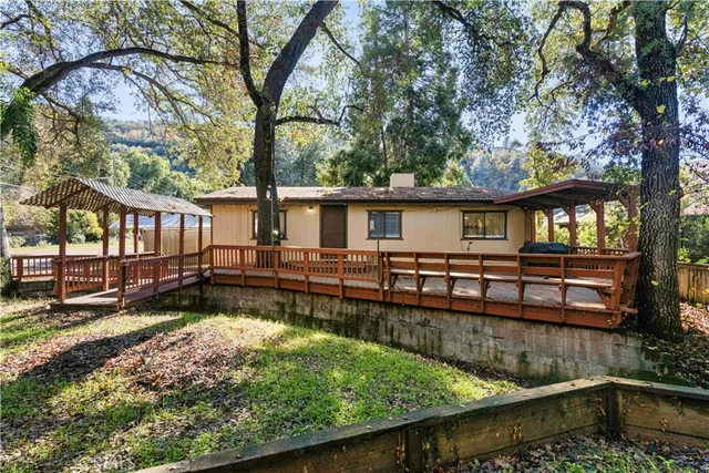 a view of a house with wooden deck and a large tree