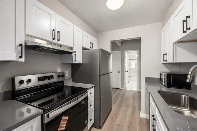 a kitchen with granite countertop a refrigerator stove and sink
