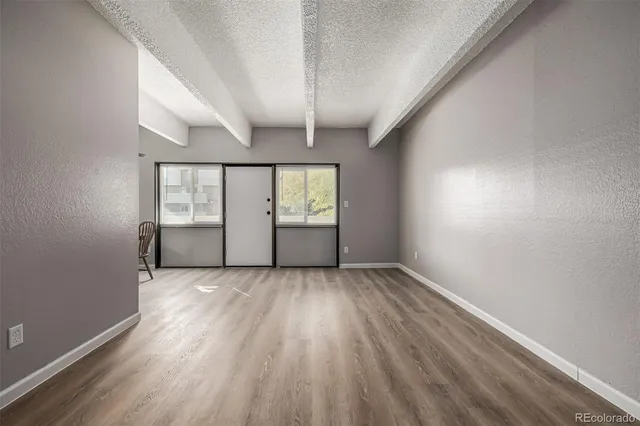 an empty room with wooden floor and windows