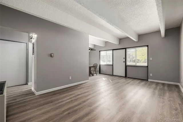 an empty room with wooden floor and windows