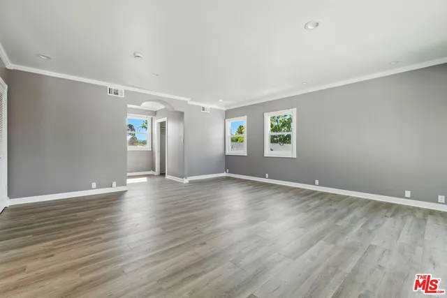 a view of an empty room with wooden floor and windows