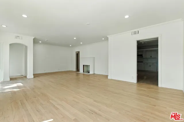 a view of an empty room with wooden floor and windows