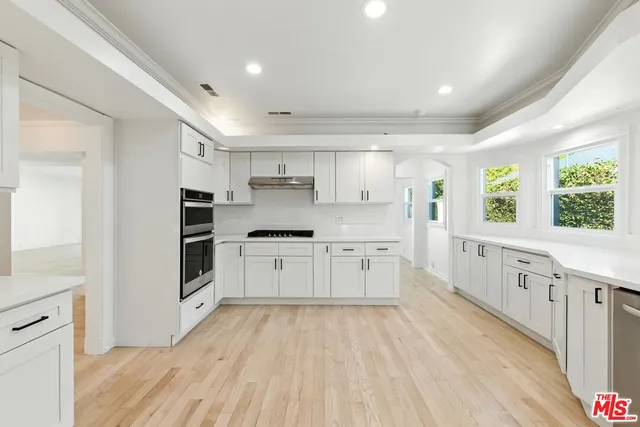 a large white kitchen with granite countertop a large window and white stainless steel appliances