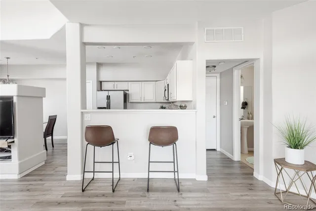 a kitchen with stainless steel appliances a dining table chairs and wooden floor