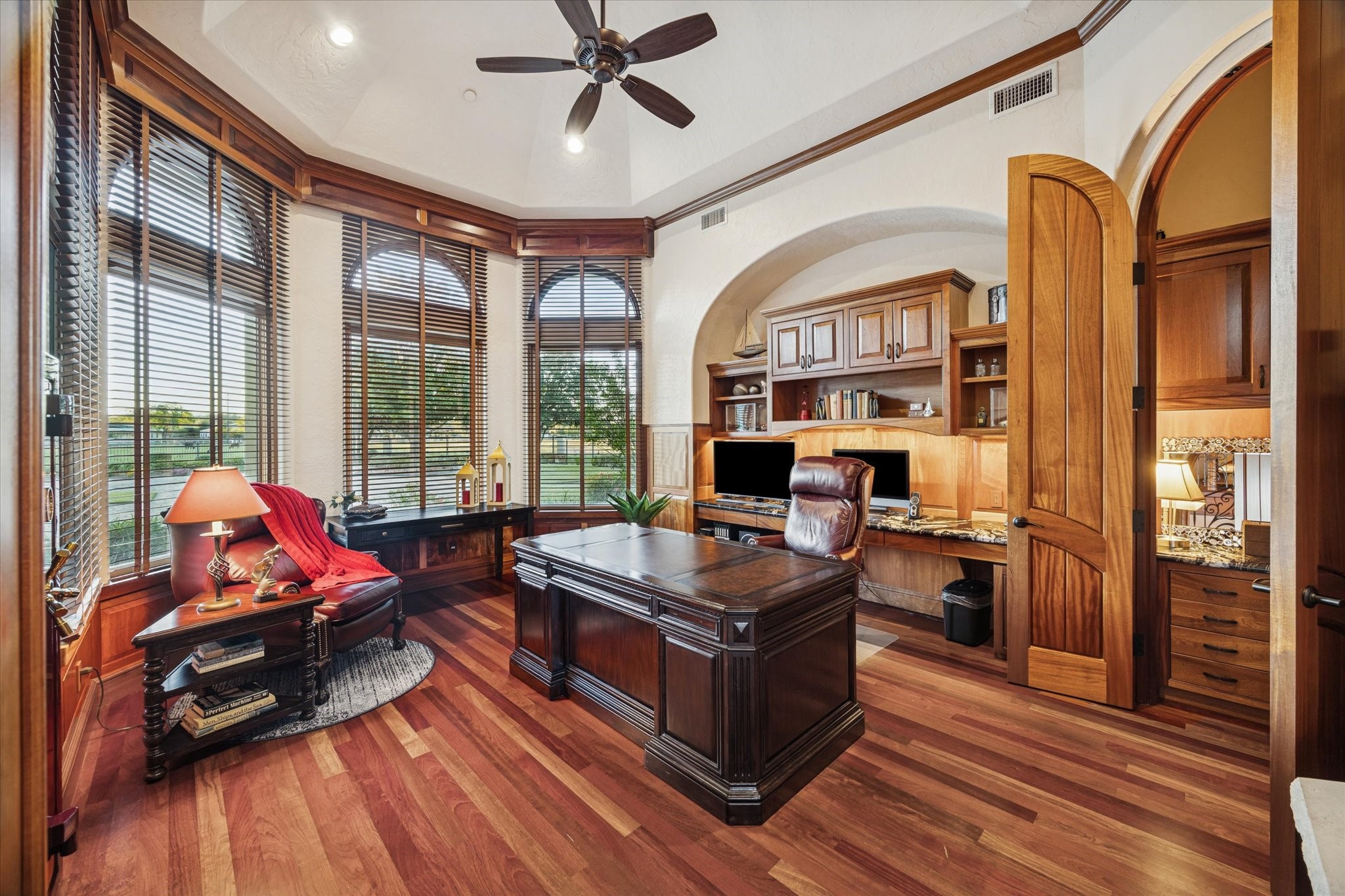 21538 Mueschke Road Tomball, TX 77377 - Photo 20 of 50 One-of-a-kind study. Located just off the foyer, this luxurious office offers privacy, natural light, and opulent views of the courtyard. It features custom mahogany built-in cabinetry with bullnose marble counters, a groin-vault ceiling, a fireplace, and a built-in desk. A bay of Palladian windows frames the courtyard and surrounding acreage. The space also includes a built-in oversized American Security safe, with a second discreet desk and safe in an adjoining annex for additional security & convenience.