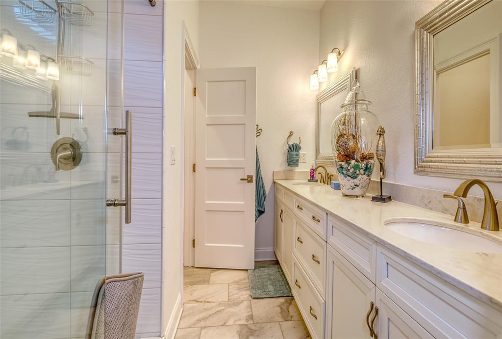 13511 Gulf Boulevard Madeira Beach, FL 33708 - Photo 13 of 30 a spacious bathroom with a double vanity sink a mirror and shower
