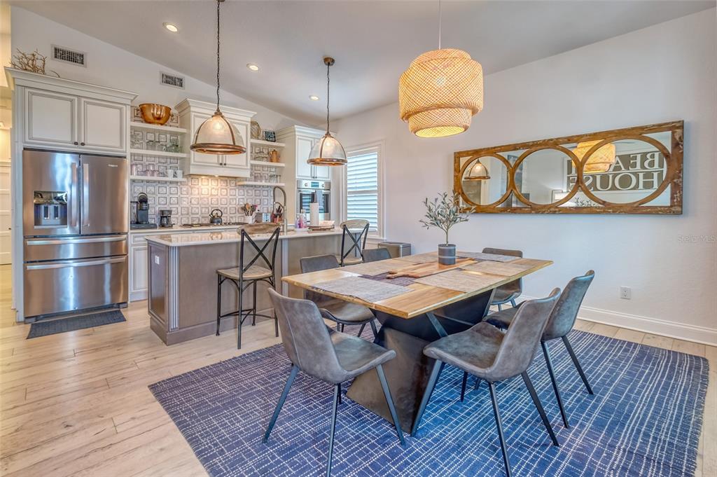13511 Gulf Boulevard Madeira Beach, FL 33708 - Photo 5 of 30 a dining room with stainless steel appliances kitchen island a table chairs and a refrigerator